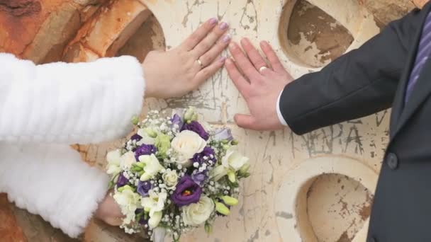 Los recién casados ponen las manos con los anillos a la pared de la iglesia — Vídeo de stock