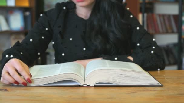 Jovem mulher lendo livro na biblioteca — Vídeo de Stock