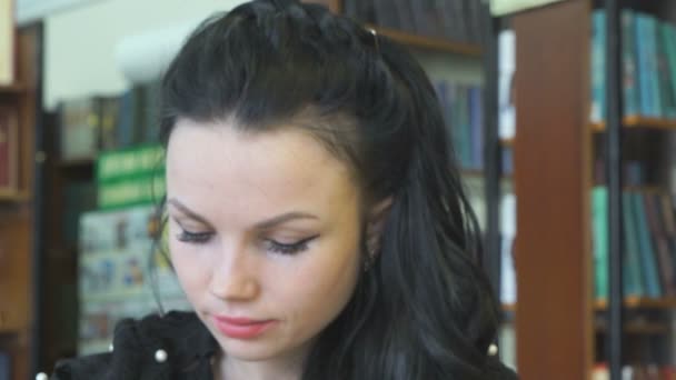 Mujer leyendo libro en la biblioteca para encontrar información — Vídeos de Stock