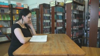 İki genç kadın kütüphanede ders kitapları okuma
