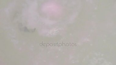 Erkek el suyla küvette pembe banyo bomba atar