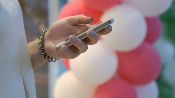 Meisje bedrijf smartphone op achtergrond van ballonnen — Stockvideo