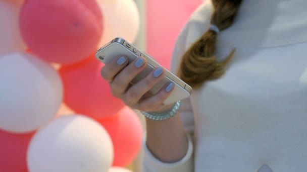 Girl holding smartphone on background of balloons — Stock Video