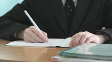 Bir çalışma kitabında bir tükenmez kalem ile öğrenci yazıyor