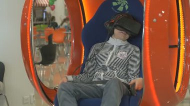 Sandalyede oturan sanal 3d kask giyen çocuk