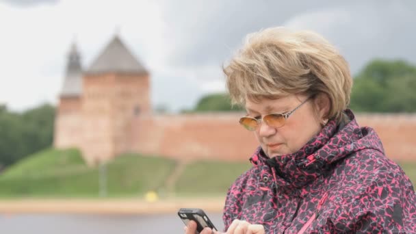 Mulher vestida de casaco esportivo segurando telefone celular — Vídeo de Stock