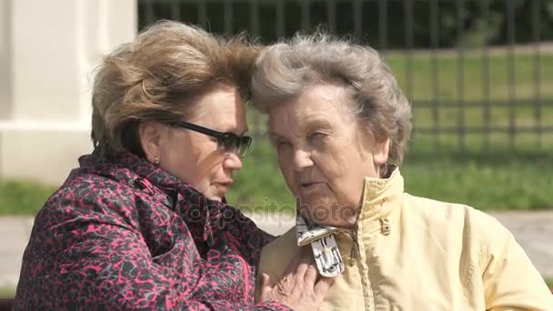 Женщина успокаивает старуху во время стресса на открытом воздухе — стоковое видео