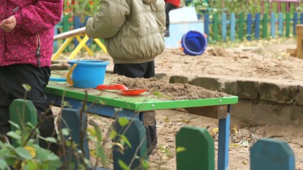 Kinderen spelen met zand op tafel in buiten — Stockvideo