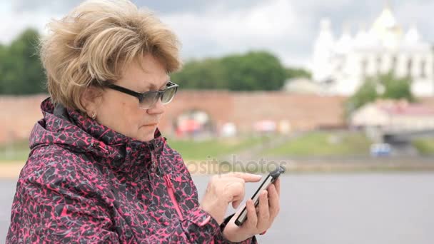 Mujer vestida con chaqueta deportiva sosteniendo teléfono móvil — Vídeos de Stock