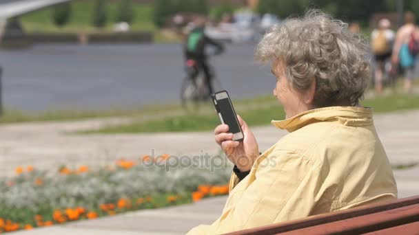 Зрелая старуха разговаривает по мобильному телефону на улице — стоковое видео