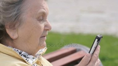 Olgun yaşlı kadın üzerinde cep telefonu açık havada söz