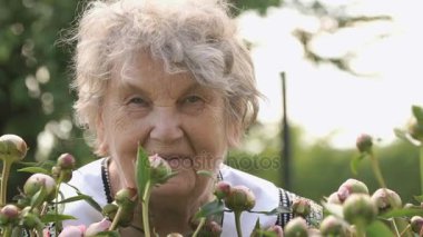 Yaşlı kadın peonies büyüyen arka planda