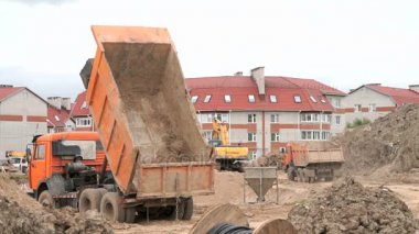 Bir inşaatta çalışan turuncu Damperli kamyonlar