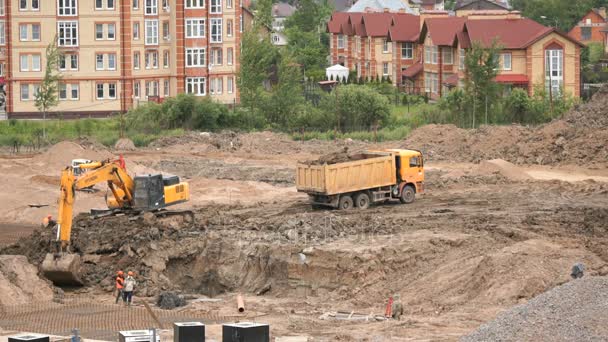 Excavator loads clay using bucket into dump truck — Stock Video