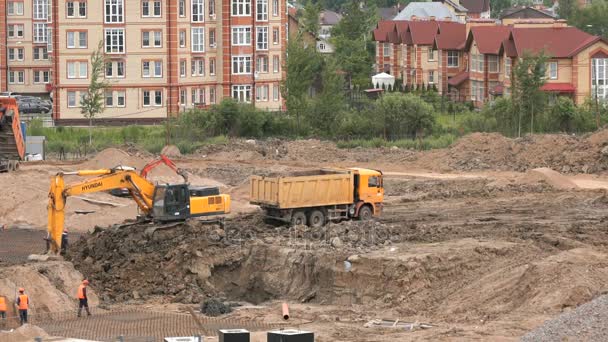 Excavator loads clay using bucket into dump truck — Stock Video