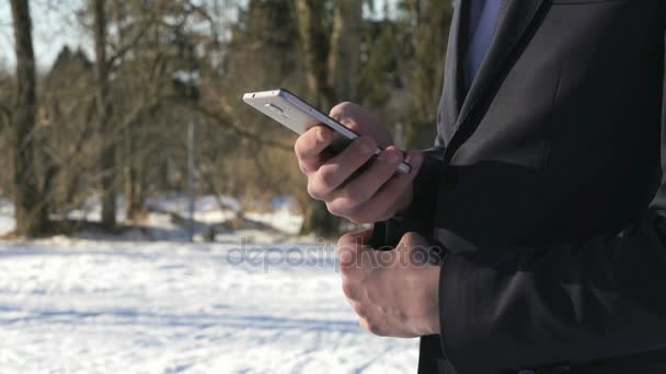 Muž, který držel stříbrný chytrý telefon na ulici v zimě — Stock video