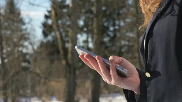 Schoolgirl holding a silver smart phone outdoors — Stock Video