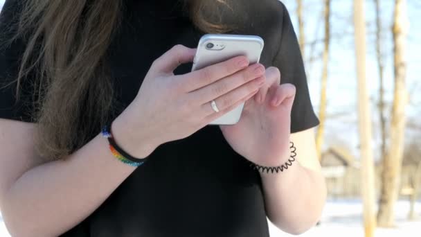 Подросток держит серебряный смартфон на улице — стоковое видео