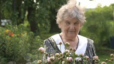 Yaşlı kadın peonies büyüyen arka planda