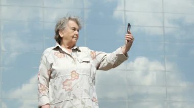 Yaşlı kadın gümüş smartphone kullanarak fotoğraf çeker