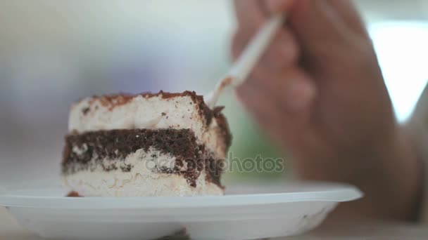 Женская рука берет кусок торта с пластиковой вилкой — стоковое видео