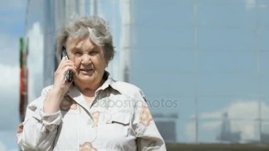 Olgun yaşlı kadın akıllı telefon açık havada kullanarak konuşuyor