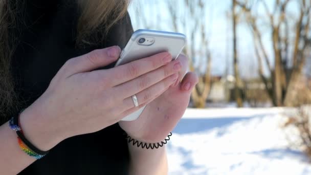 Skolflicka håller en silver smarta telefonen utomhus — Stockvideo