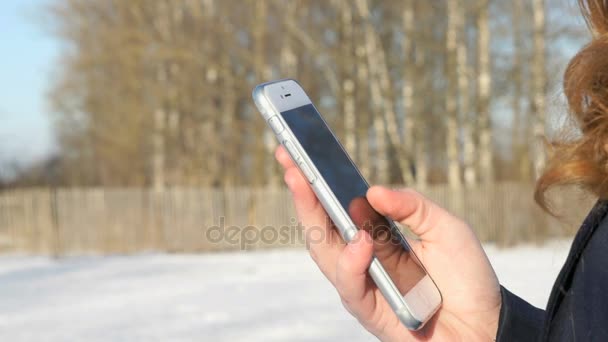 Primer plano de una chica que sostiene el teléfono inteligente al aire libre — Vídeos de Stock