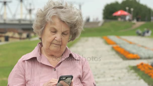 Lachende rijpe oude vrouw houdt een slimme telefoon — Stockvideo