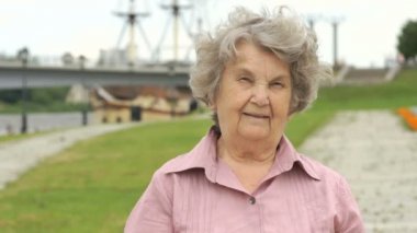 Gülümseyen yaşlı kadın gümüş cep telefonu gösterir