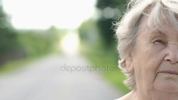 Половина лица серьезной пожилой женщины на улице — стоковое видео