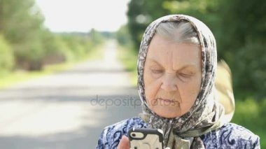 Olgun yaşlı kadın gümüş smartphone açık havada tutar