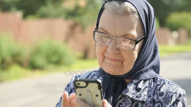 Χαμογελώντας ηλικιωμένη γυναίκα συνομιλίες χρησιμοποιώντας smartphone — Αρχείο Βίντεο