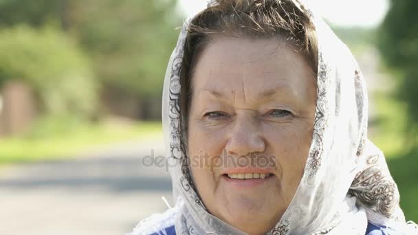 Glimlachend volwassen vrouw in witte zakdoek buitenshuis — Stockvideo