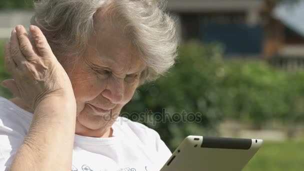 高齢者女性は屋外にコンピューター タブレットを保持しています。 — ストック動画