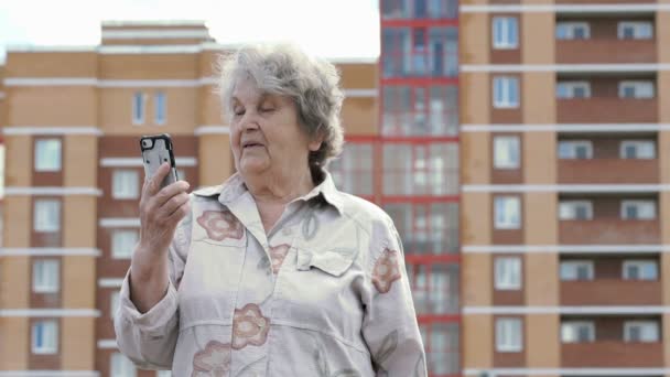 Vecchia donna anziana parla utilizzando smart phone all'aperto — Video Stock