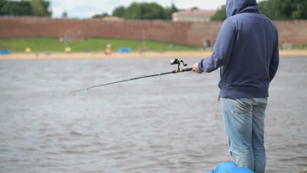 Человек рыбачит на берегу реки — стоковое видео