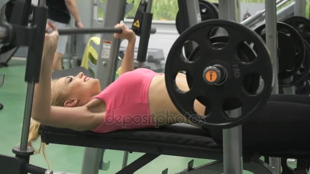 Gyönyörű szőke lány részt vesz az edzőteremben beltéri — Stock videók