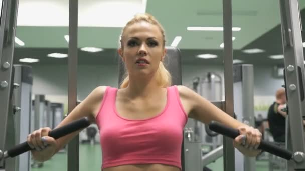 Hermosa chica rubia ocupada en el gimnasio en el interior — Vídeos de Stock