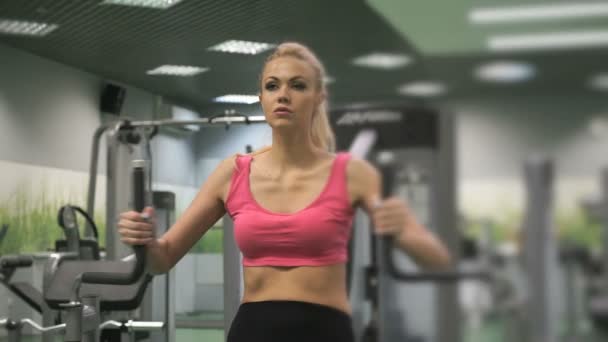 Hermosa chica rubia ocupada en el gimnasio en el interior — Vídeos de Stock