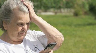 Gülümseyen olgun yaşlı kadın bir cep telefonu tutan