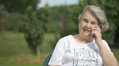Gülümseyen yaşlı kadın bir cep telefonu kullanarak söz