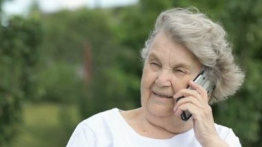 Yaşlı kadın bir cep telefonu açık havada kullanarak söz