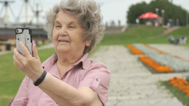 Rijpe oude vrouw neemt foto's met behulp van een slimme telefoon — Stockvideo