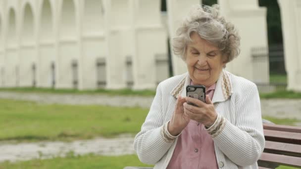 成熟した古い女性が屋外銀スマート フォンを保持します。 — ストック動画