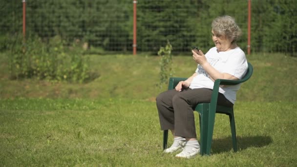 高齢者女性のスマート フォンを屋外で使う話 — ストック動画