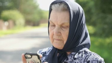 Olgun yaşlı kadın gümüş smartphone açık havada tutar