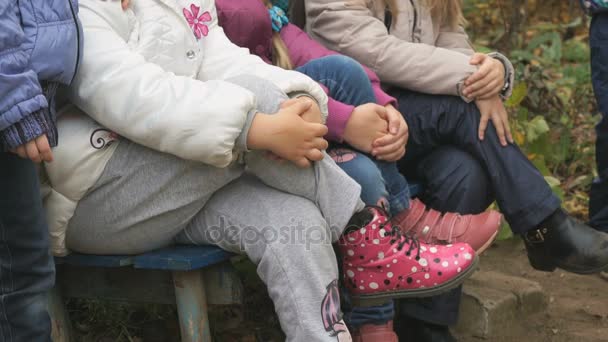 Children sit on bench in yard in autumn — Stock Video