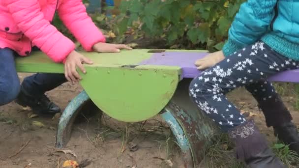 Две маленькие девочки катаются на качелях — стоковое видео