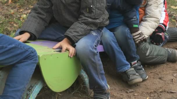 Група дітей, які катаються на гойдалках, сидять разом — стокове відео